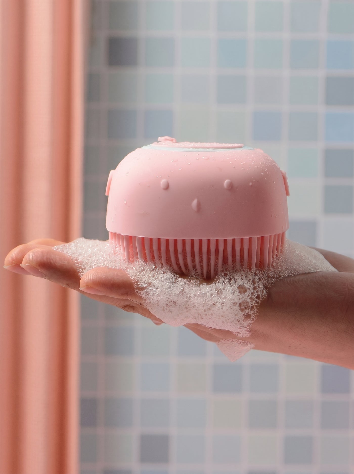 Pink silicone brush with foam in shower setting – Malpetit