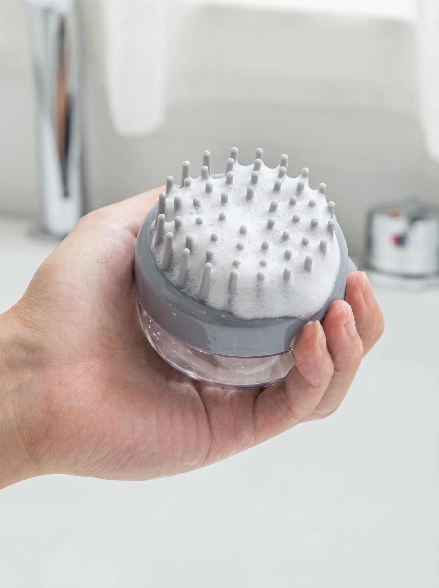 Grey silicone bath brush in hand with rich foam – Malpetit
