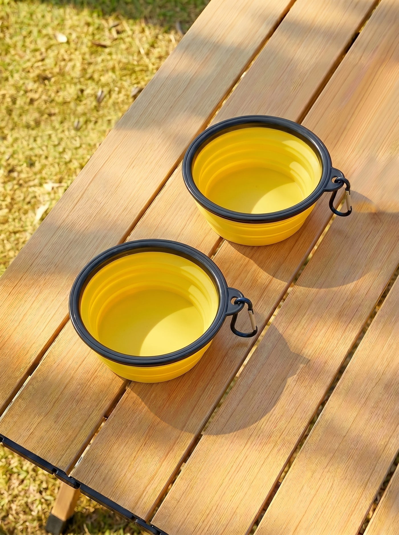 Two yellow foldable travel bowls on wooden table outdoors – Malpetit