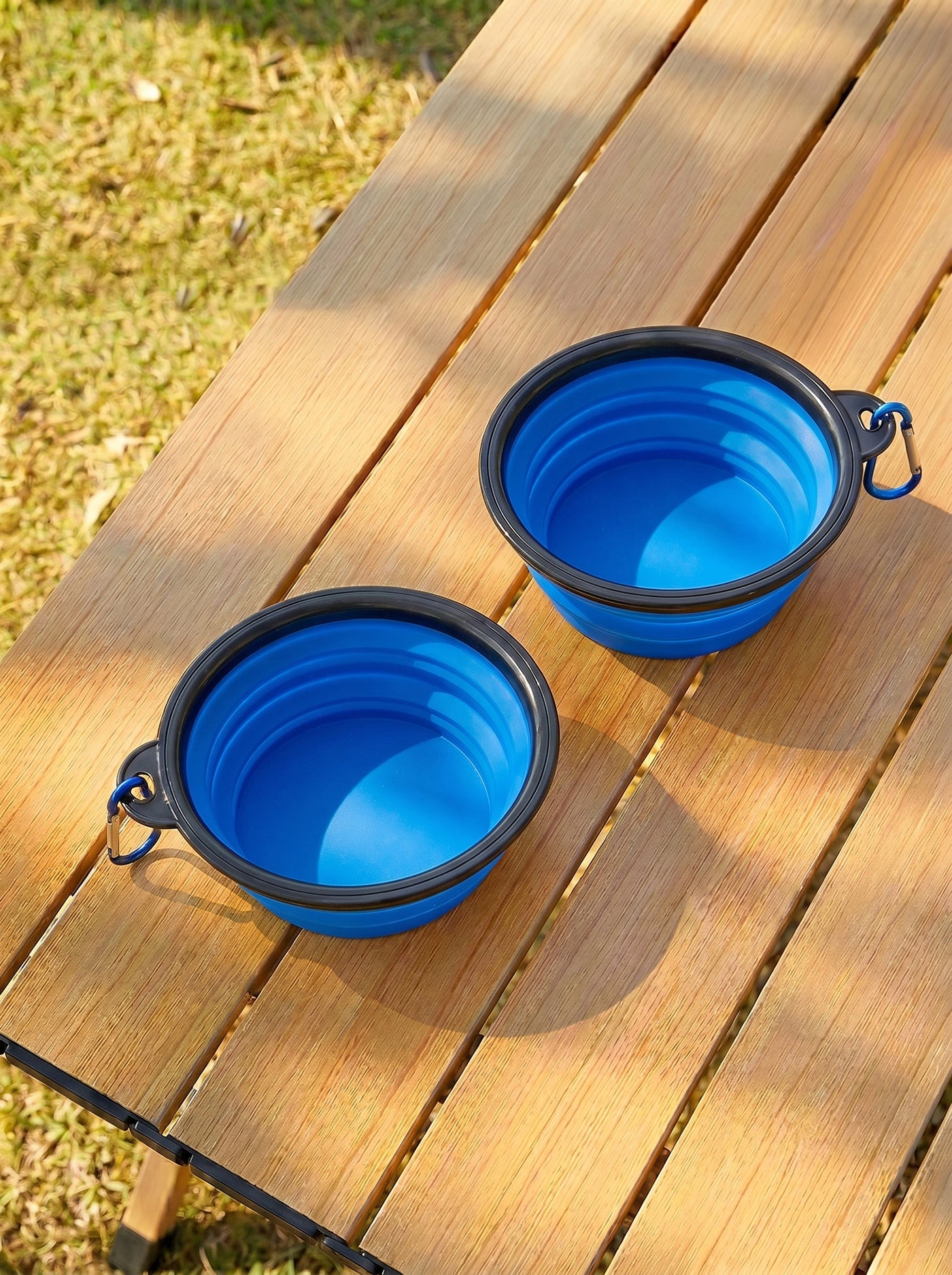 Two blue foldable travel bowls on wooden table outdoors – Malpetit